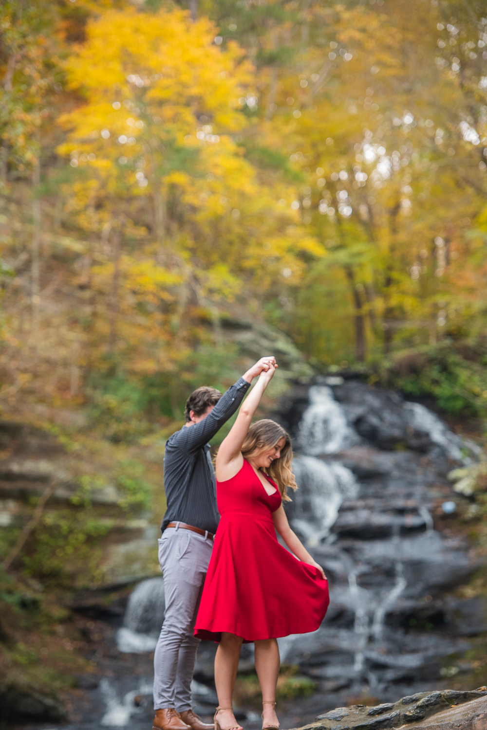 couple twirling in front of waterfall